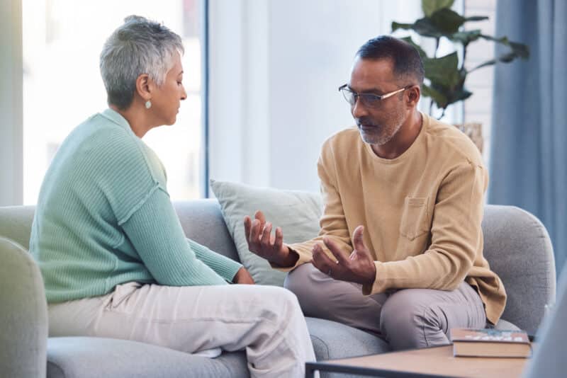 Couple talking on a sofa about addiction treatment.