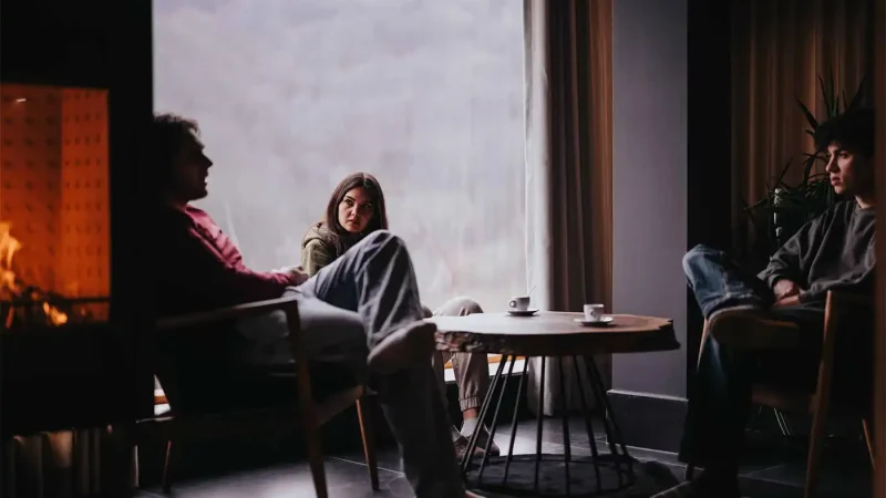 Family talking to a loved one about addiction recovery in a cozy home interior with fireplace.