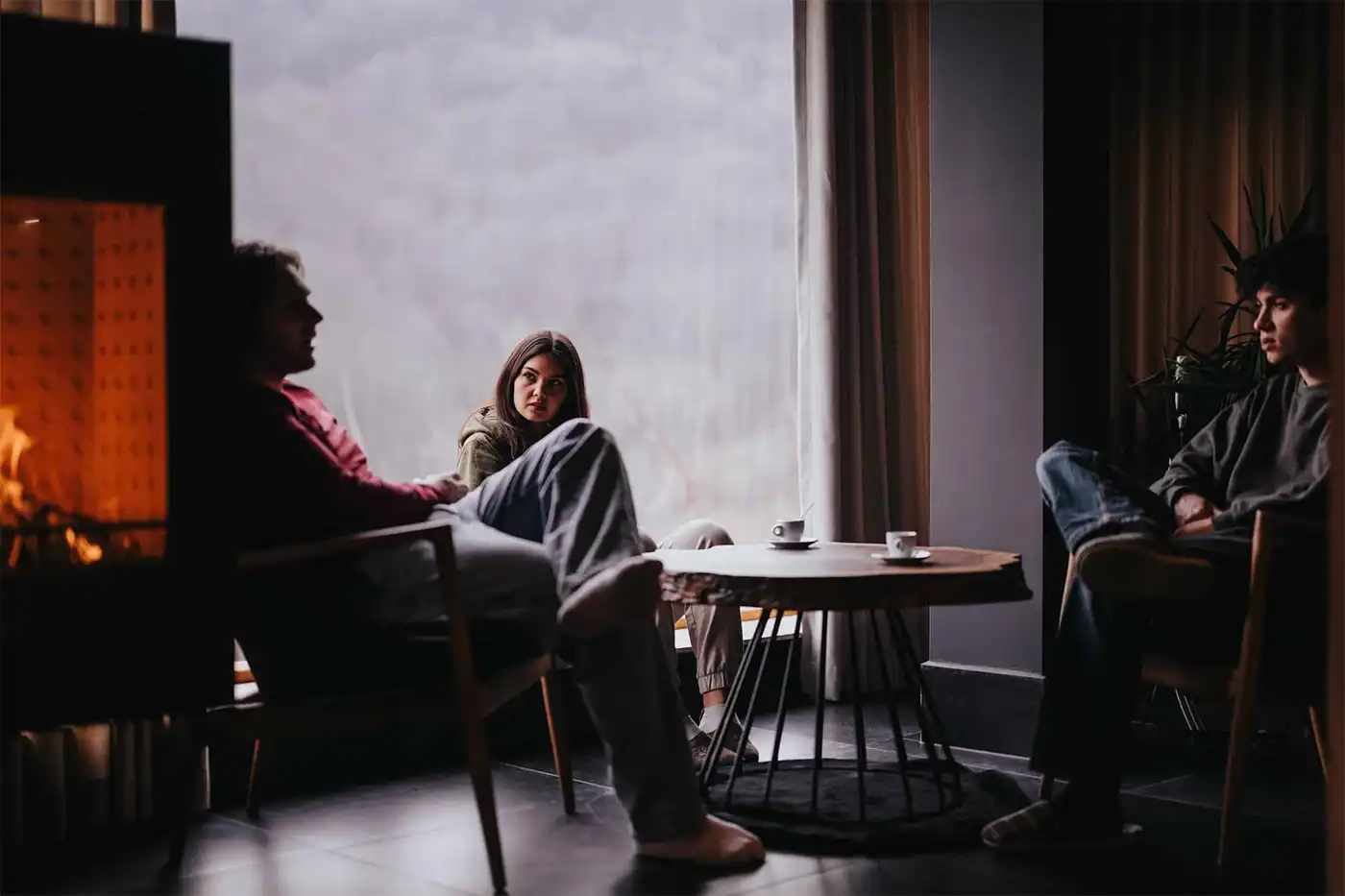 Family talking to a loved one about addiction recovery in a cozy home interior with fireplace.