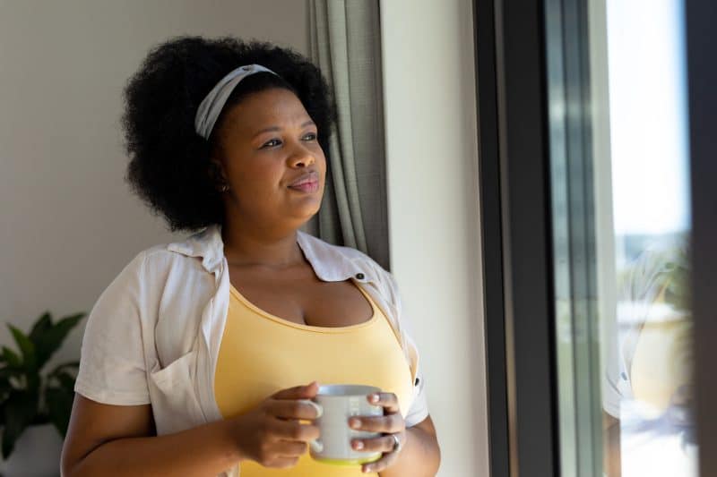 Woman looking out the window wondering "Is an Eating Disorder a Mental Illness?"