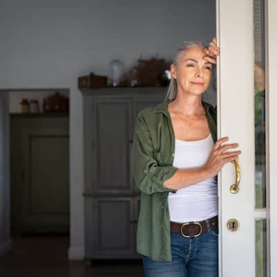 Woman leaning on an open door happy about a decision to go to addiction rehab in Georgia.