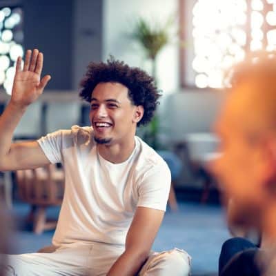 smiling man raising his hand in group at Recover Now best rehab centers in Georgia.