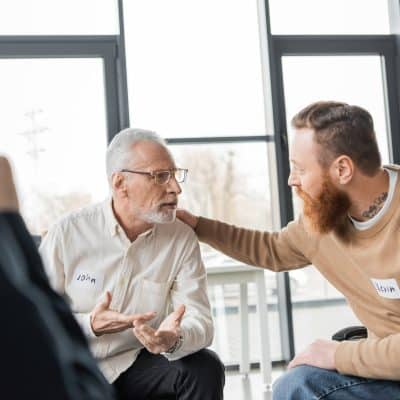 Middle aged man with alcohol addiction sharing problem with group in rehab center.