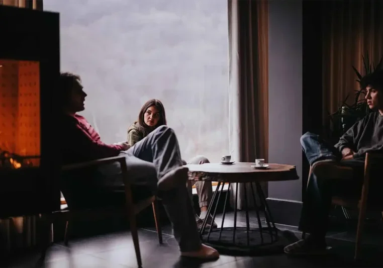 Family talking to a loved one about addiction recovery in a cozy home interior with fireplace.